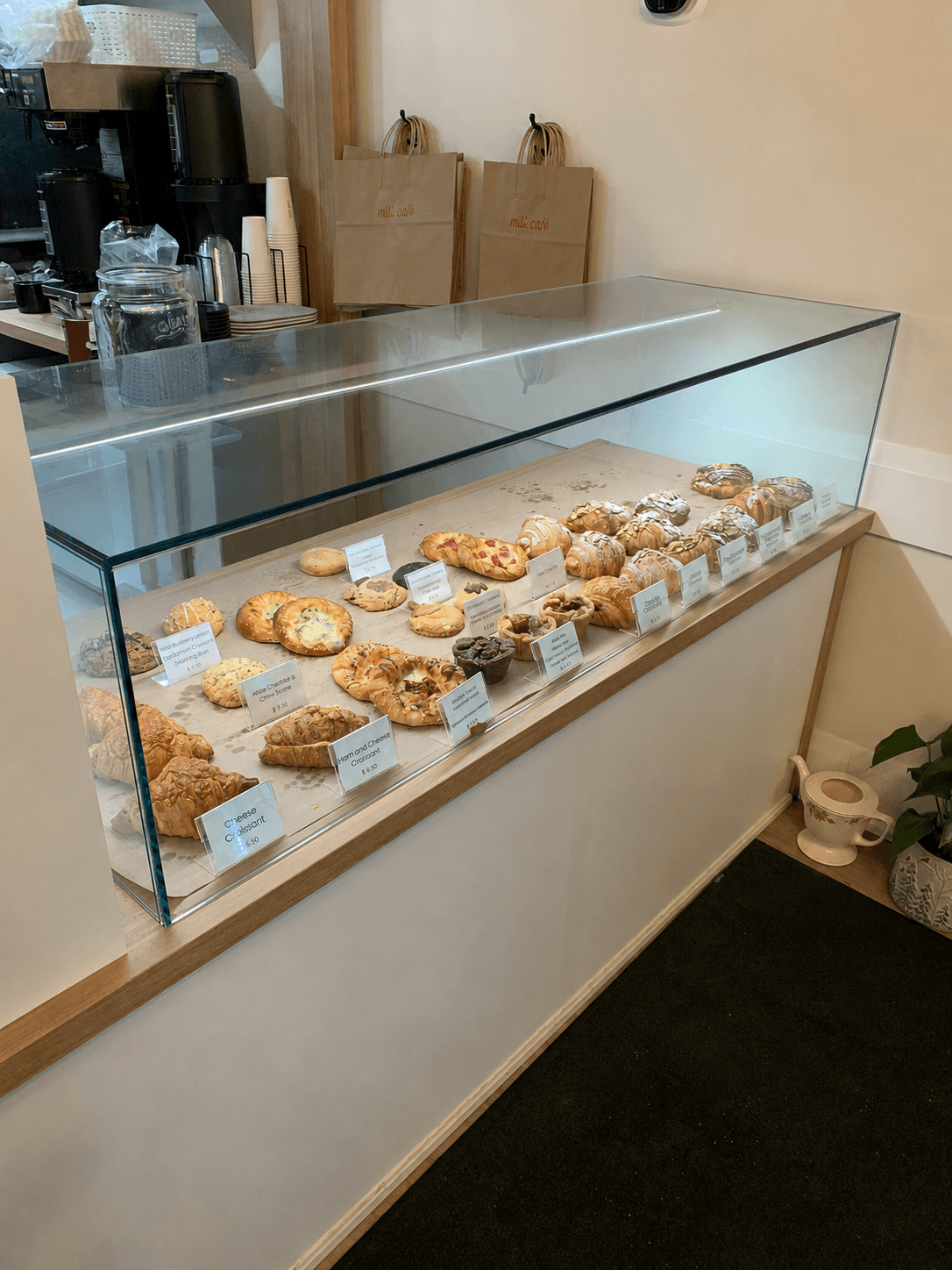 Frameless glass bakery display case showcasing a row of pastries and croissants