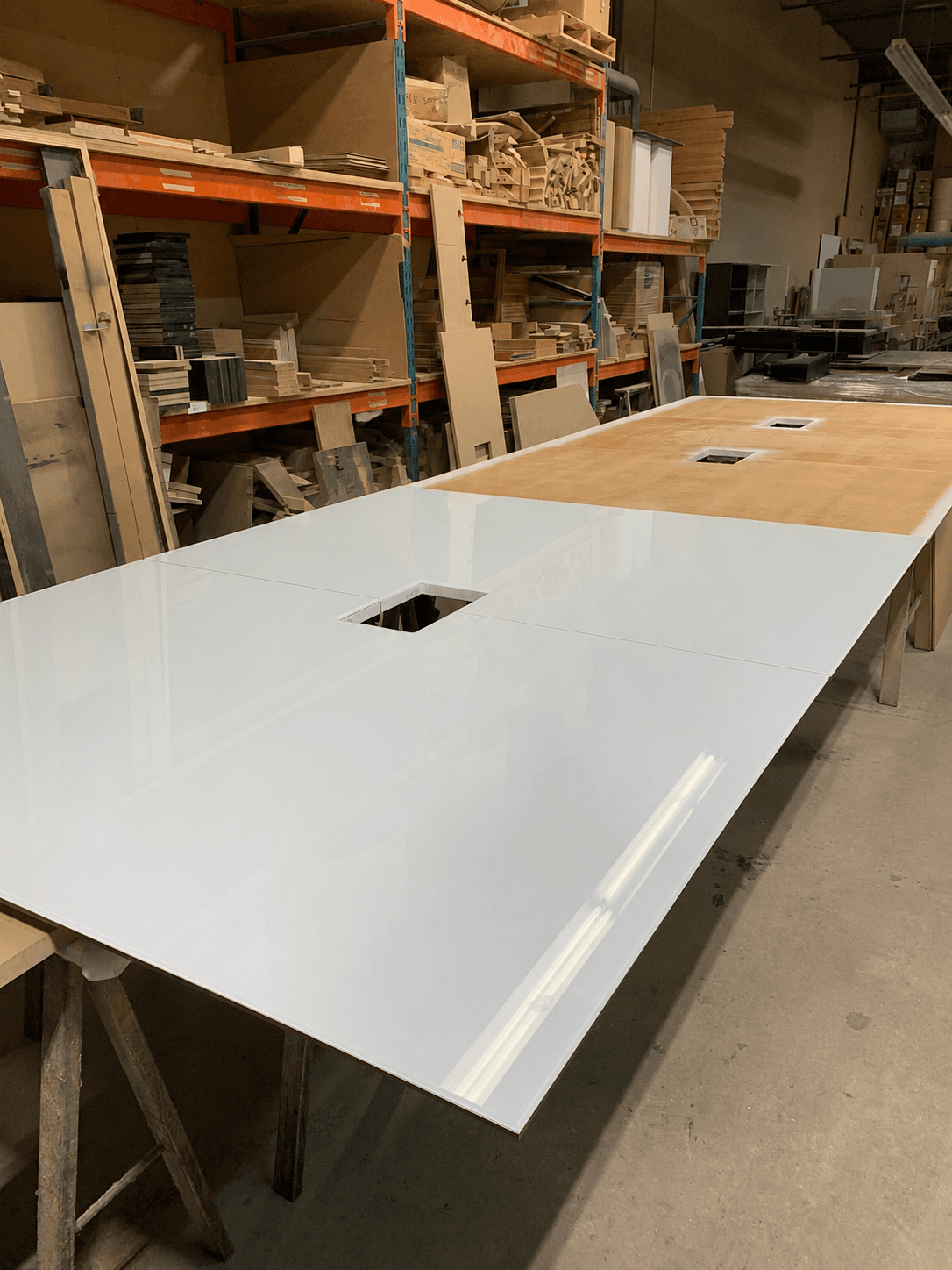 Custom-cut glossy white glass panels being fabricated at the shop, resting on sawhorses