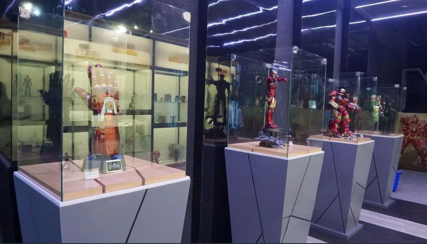 Museum-style glass display pedestals with individual cases protecting collectible figures